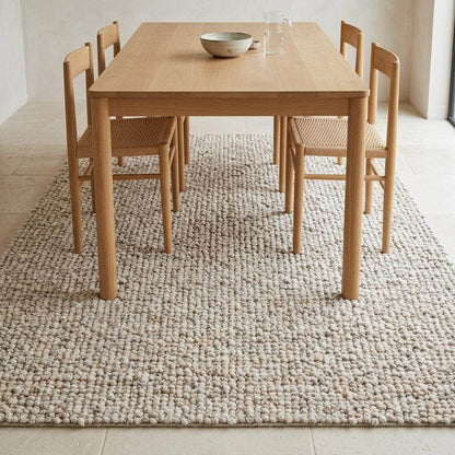 Handwoven chunky wool rug with natural beige pebble texture in Scandinavian living room setting