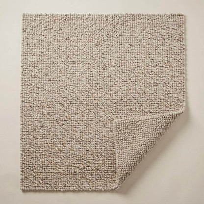 Handwoven chunky wool rug with natural beige pebble texture in Scandinavian living room setting