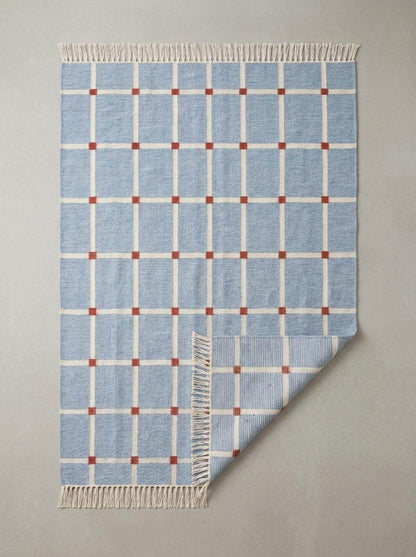 Handwoven flatweave blue grid rug with terracotta accents in modern farmhouse living room