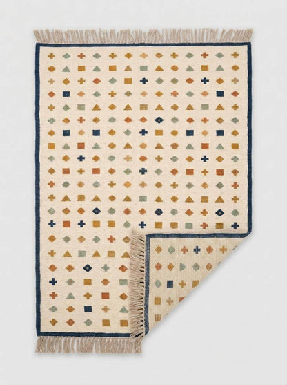 Ivory wool flatweave kilim rug with navy border and geometric scatter motif in a living room setting