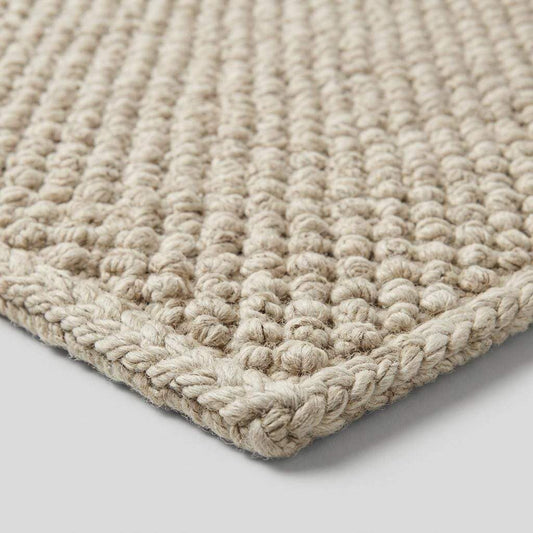 Handwoven chunky wool pebble rug in neutral tones, textured Scandinavian minimalist carpet for cozy living room decor