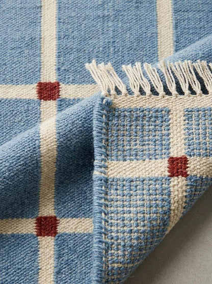 Handwoven flatweave blue grid rug with terracotta accents in modern farmhouse living room