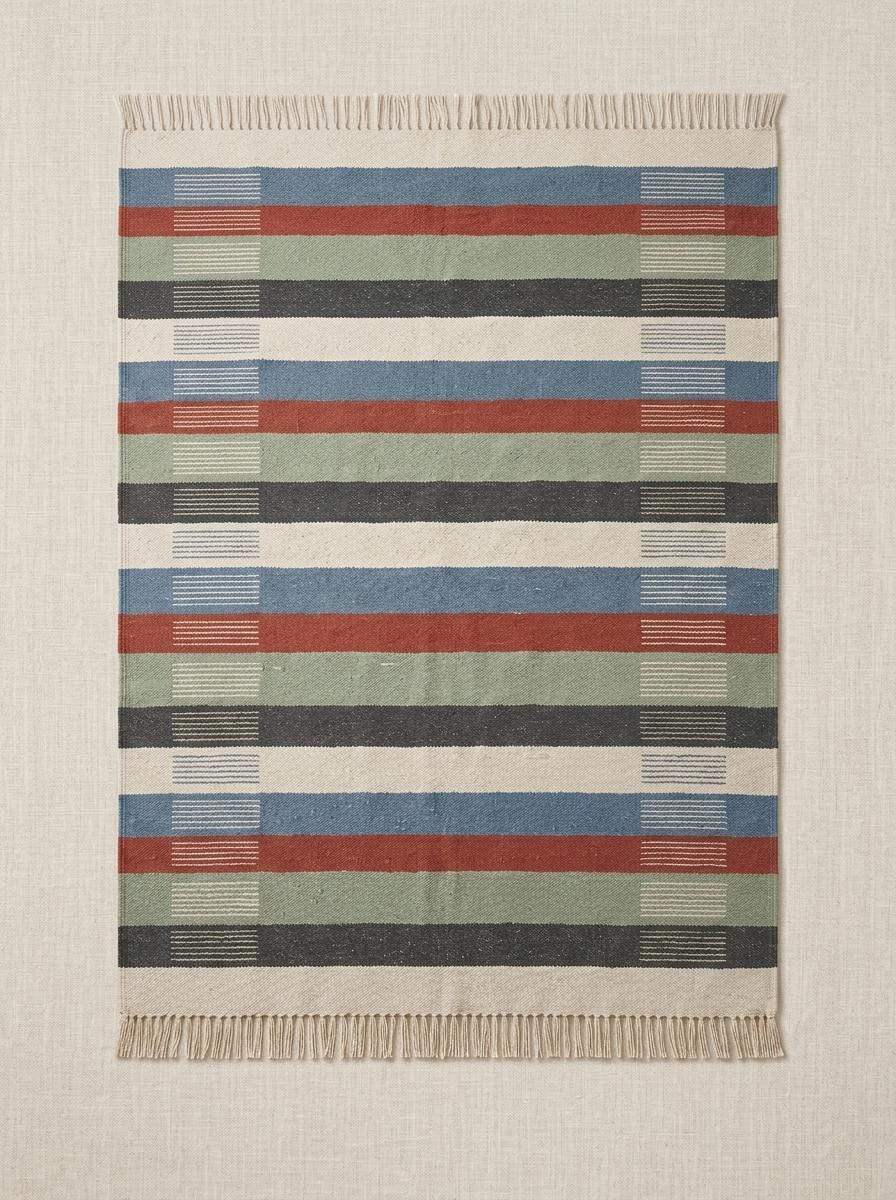 Handwoven striped wool flatweave rug in blue, rust, sage, and ivory with cotton fringe