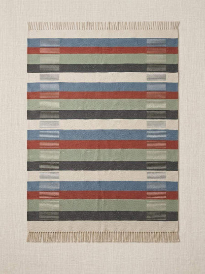 Handwoven striped wool flatweave rug in blue, rust, sage, and ivory with cotton fringe