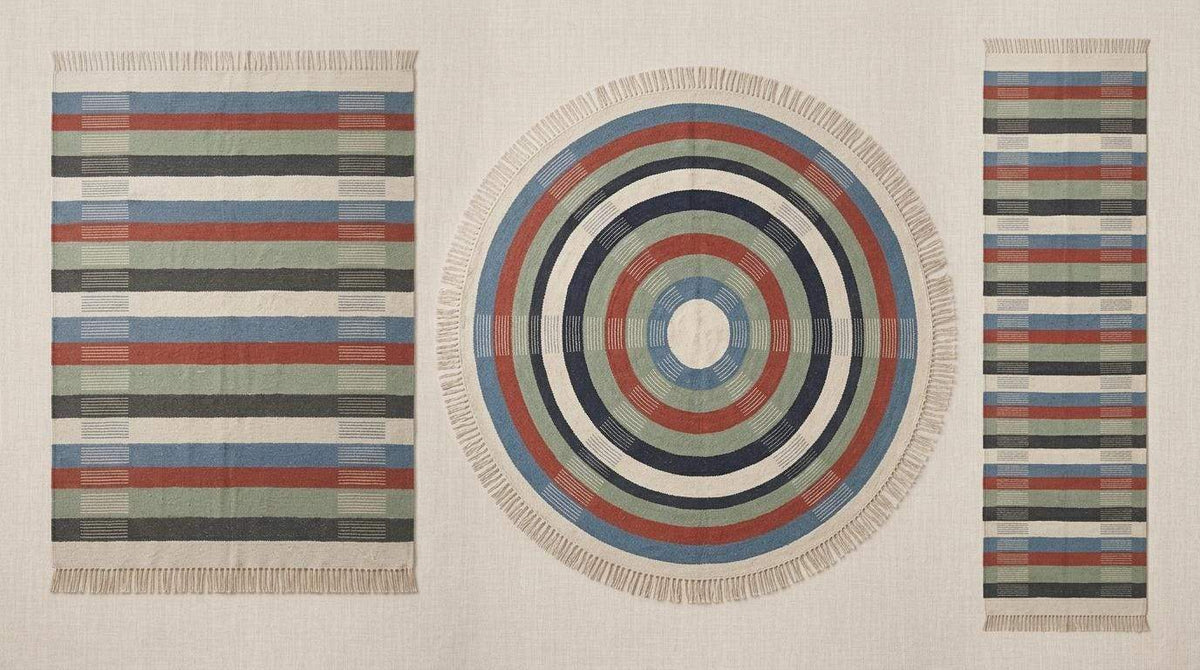 Handwoven striped wool flatweave rug in blue, rust, sage green, and ivory with cotton fringe
