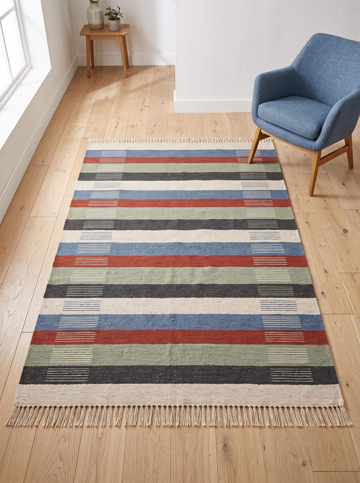 Handwoven striped wool flatweave rug in blue, rust, sage, and ivory with cotton fringe