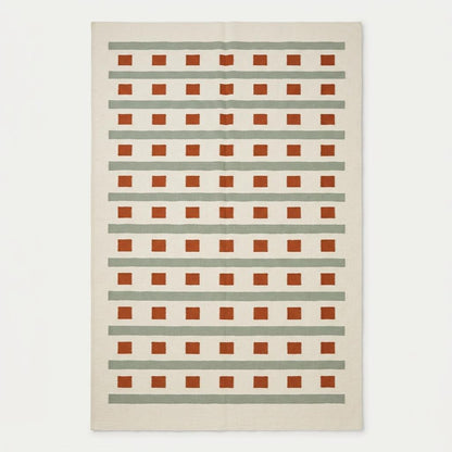 Handwoven ivory sage green flatweave dhurrie rug with terracotta stripes and squares in living room setting