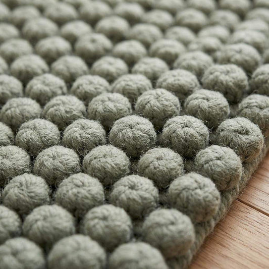 Sage green hand woven wool area rug with pebble texture bobble weave design