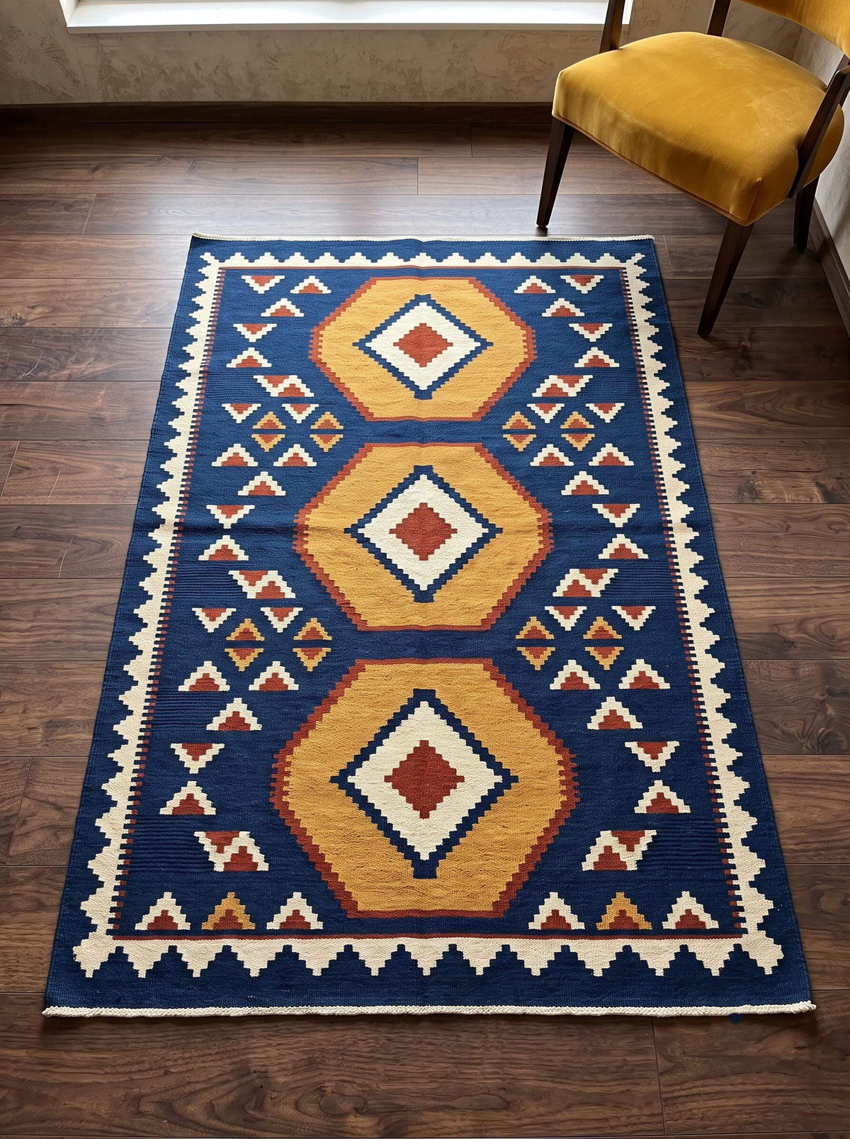 Handwoven blue kilim rug with golden hexagon medallions and ivory serrated border on indigo background