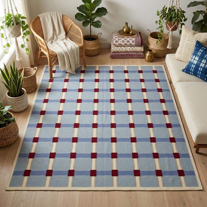 Pale blue flatweave wool rug with red and ivory grid check pattern in modern living room setting