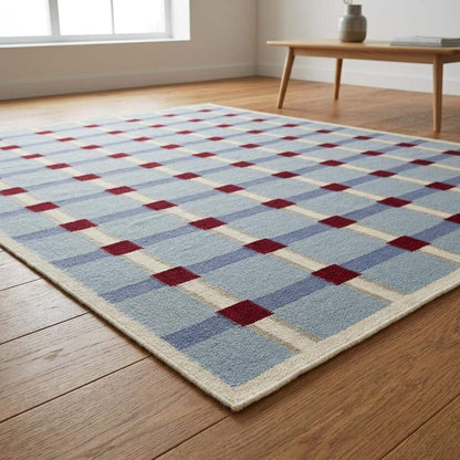 Pale blue flatweave wool rug with red grid check pattern in modern living room setting