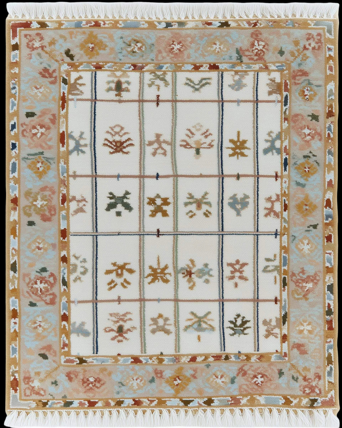 Ivory grid floral area rug with pastel floral border and fringed edges on stone floor