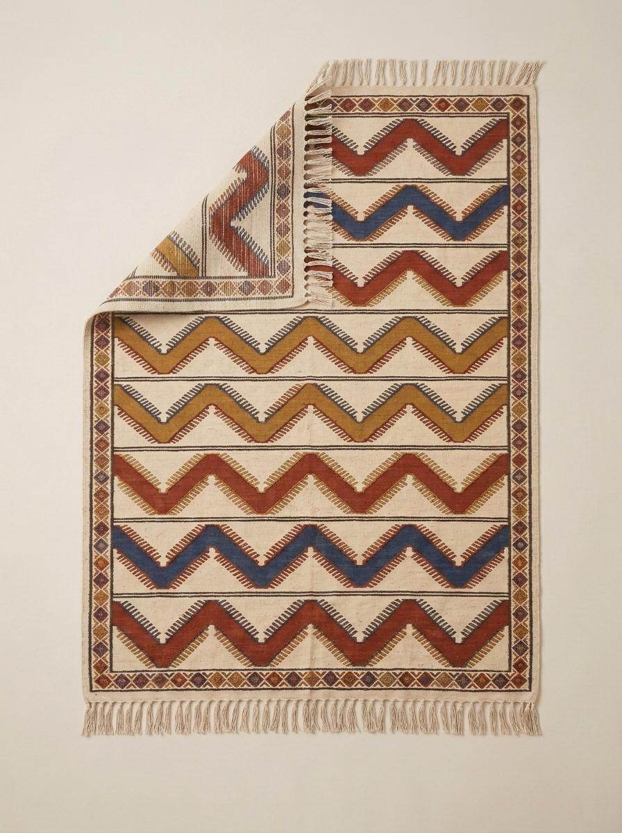 Handwoven wool flatweave rug with ivory, rust, and blue chevron pattern