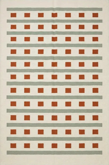 Handwoven ivory sage green flatweave dhurrie rug with terracotta stripes and squares in living room setting