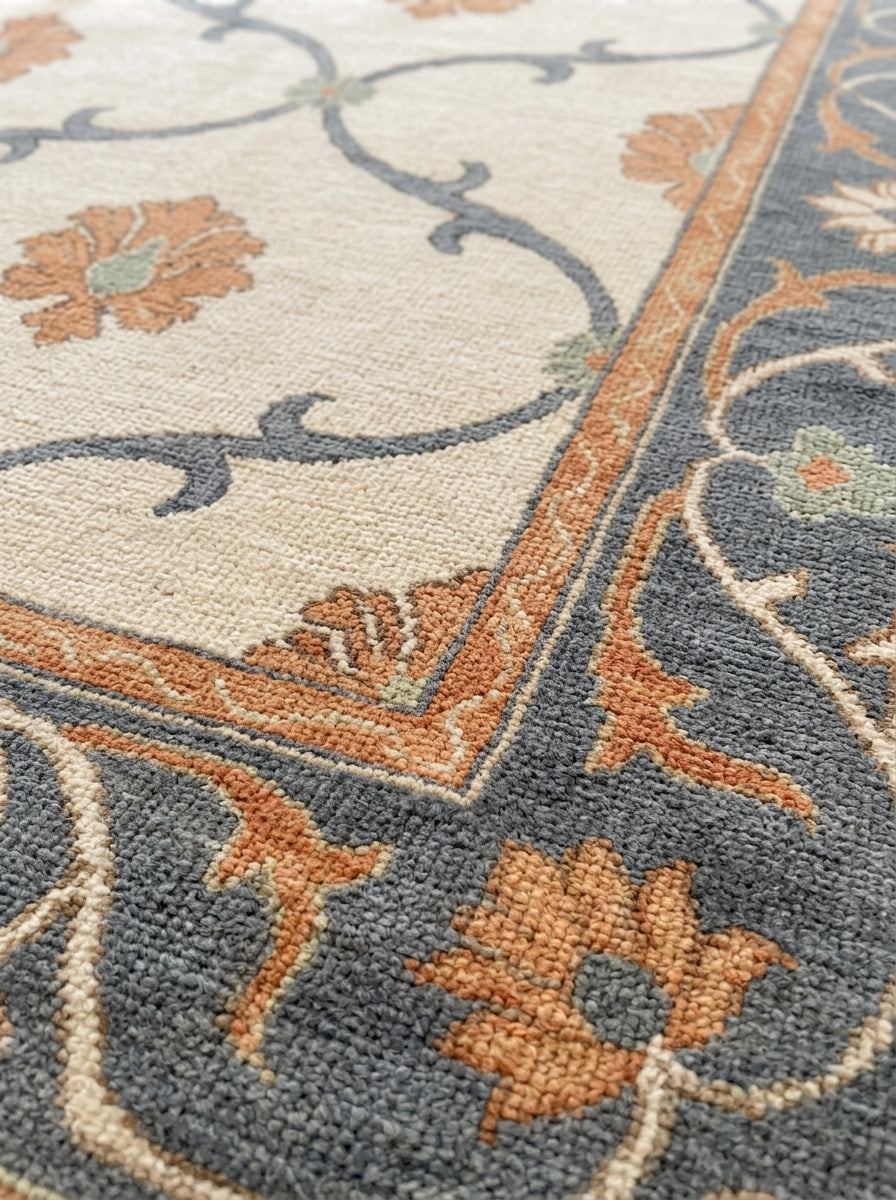 Ivory Trellis Rug with a hand-knotted wool pile, peach blossoms and slate blue vines on ivory, with a floral border