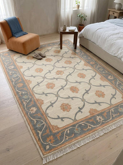 Ivory Trellis Rug in hand-knotted wool, with peach floral motifs in a slate blue vine lattice and border