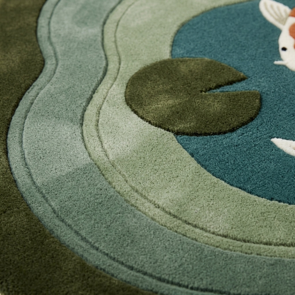 Koi Pond Rug in tufted wool with layered sage and seafoam ripples, an olive lily pad and partial koi