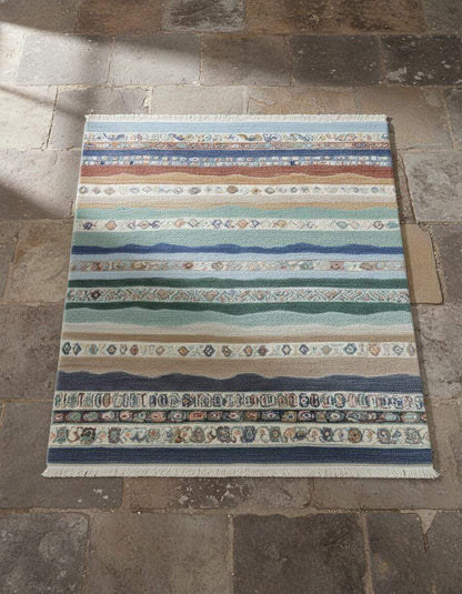 Multicolor striped area rug with horizontal boho coastal fringe design in blues, greens, sand, taupe, clay, and terracotta colors