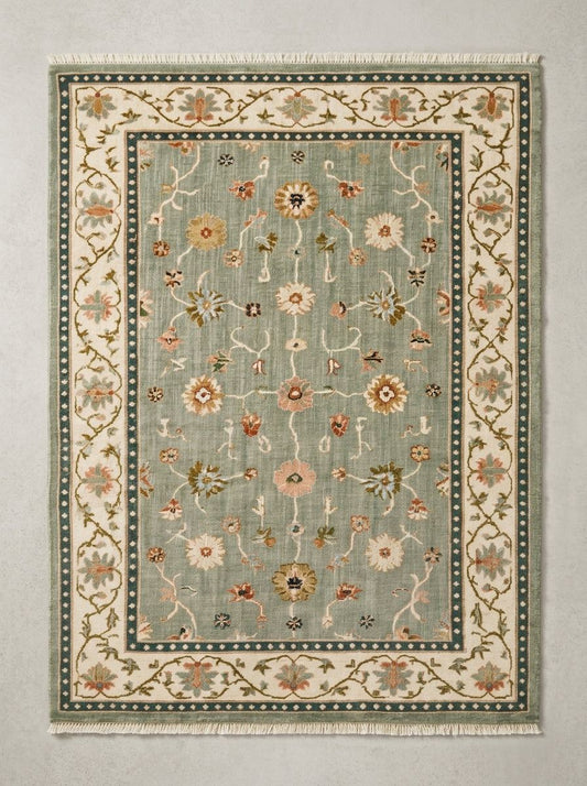 Oushak Hand Knotted Rug in muted sage wool, with scattered floral vines, an ivory botanical border, and teal dotted bands.