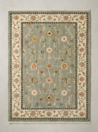 Oushak Hand Knotted Rug in muted sage wool, with scattered floral vines, an ivory botanical border, and teal dotted bands.