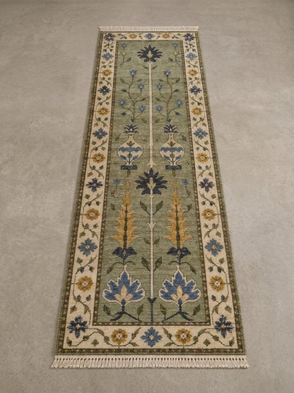 Hand Knotted Oushak Runner Rug in sage green wool, with floral vase motifs, blue and mustard accents, ivory border and fringe.