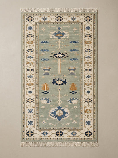 Hand Knotted Oushak Runner Rug in muted sage green wool, with ivory floral border, blue and amber urn motifs, and fringe.