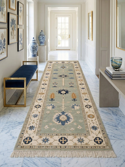 Hand Knotted Oushak Runner Rug in muted seafoam green wool, with ivory floral borders, blue and amber motifs, and fringe.