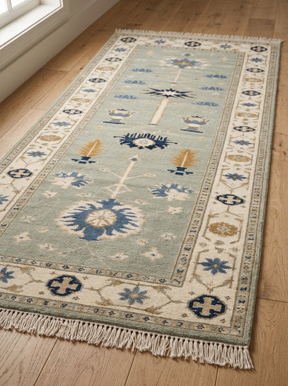 Hand Knotted Oushak Runner Rug in muted seafoam wool, with ivory floral border, navy and amber motifs, and fringe.