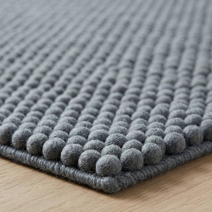 Chunky Wool Rug with a thick slate gray wool texture, featuring closely spaced rows of rounded woven pebbles.