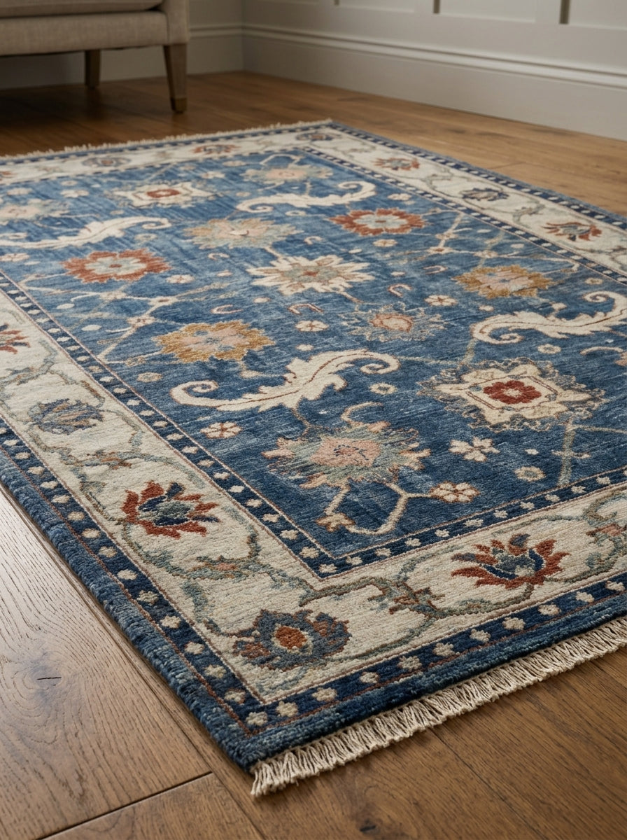 Oushak Hand Knotted Rug in blue wool, with ivory floral border, scrolling motifs, rust and gold flowers, and fringed ends.