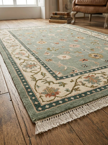 Oushak Hand Knotted Rug in muted sage green wool, with scattered floral motifs, an ivory vine border, teal bands and fringe.
