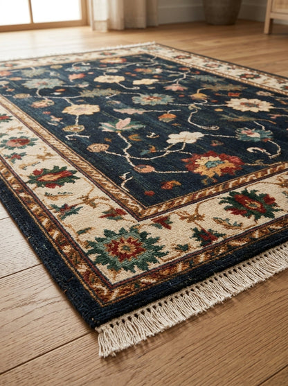 Oushak Hand Knotted Rug in midnight blue wool, with scattered multicolour florals, ivory palmette border and fringed ends.