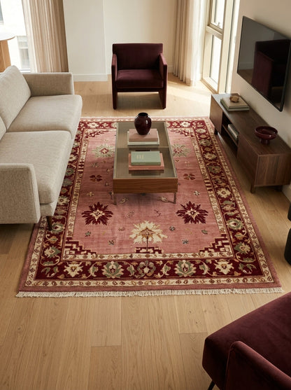Oushak Hand Knotted Rug in dusty rose wool, with scattered floral motifs, burgundy border and ivory fringe.