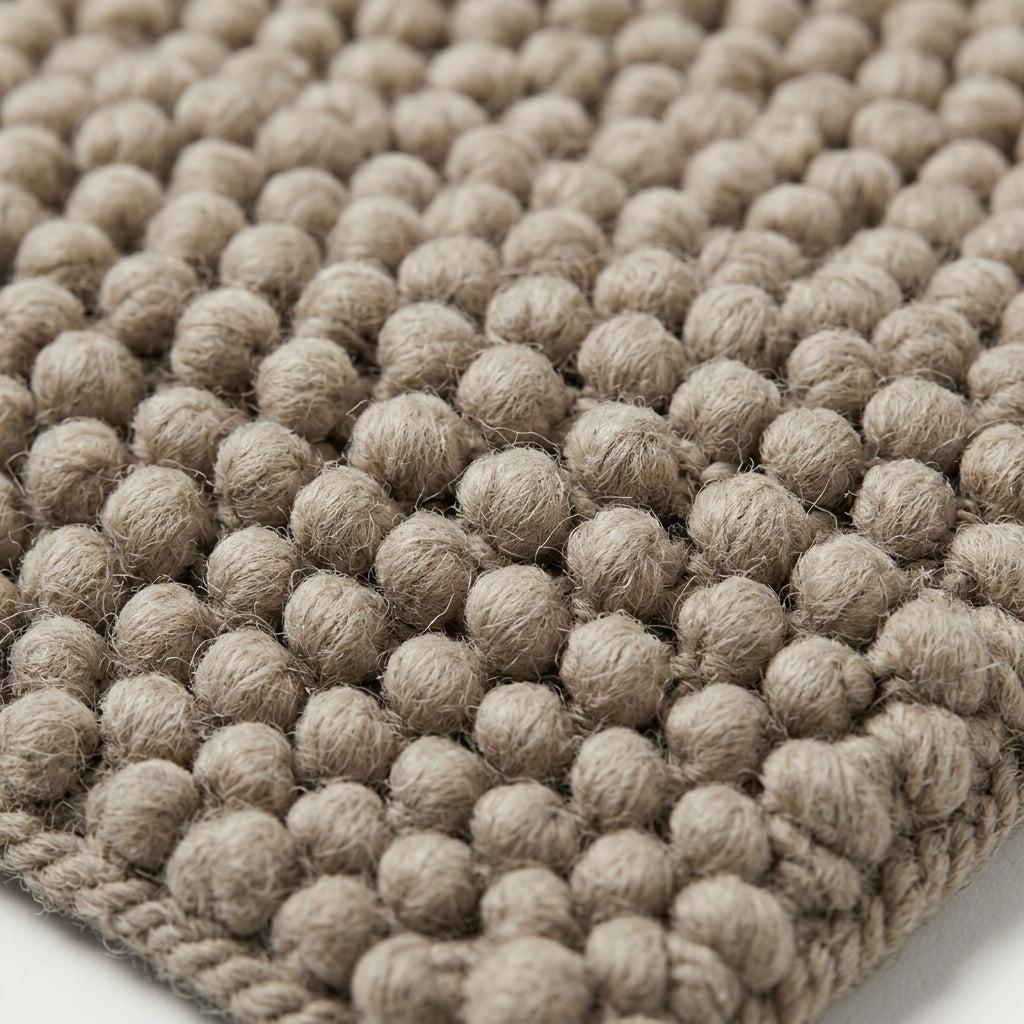 Chunky Wool Rug in mottled taupe greige, with thick, fuzzy wool fibers, raised pebble knots and a braided edge.