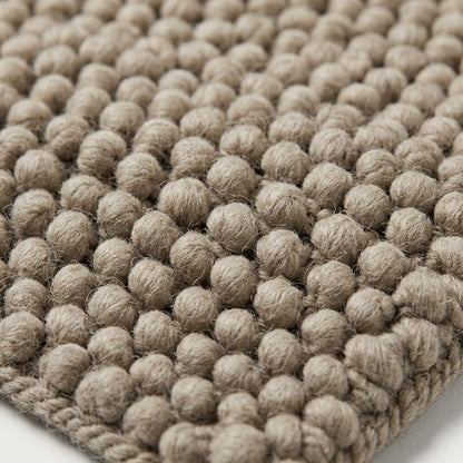 Chunky Wool Rug in mottled taupe greige, with thick, fuzzy wool fibers, raised pebble knots and a braided edge.