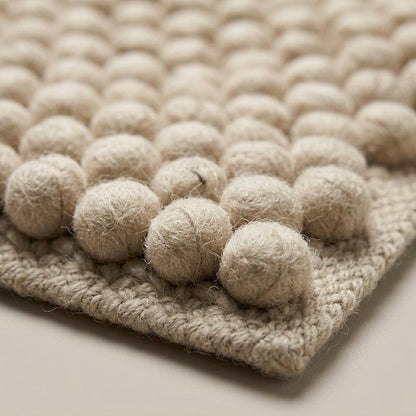 Chunky Wool Rug in oatmeal beige wool with chunky woven edging and raised, handwoven pebble rows for a thick textured finish.