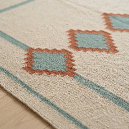 Southwestern Flatweave Wool Rug in heathered beige with sage borders and terracotta stepped diamonds with sage centres