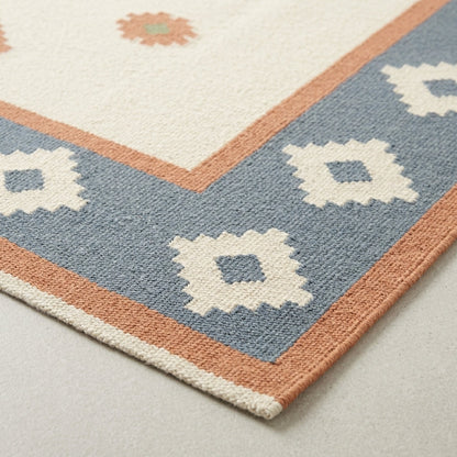 Southwestern Flatweave Wool Rug in dusty blue, ivory and peach, with stepped geometric motifs and a flatwoven texture.
