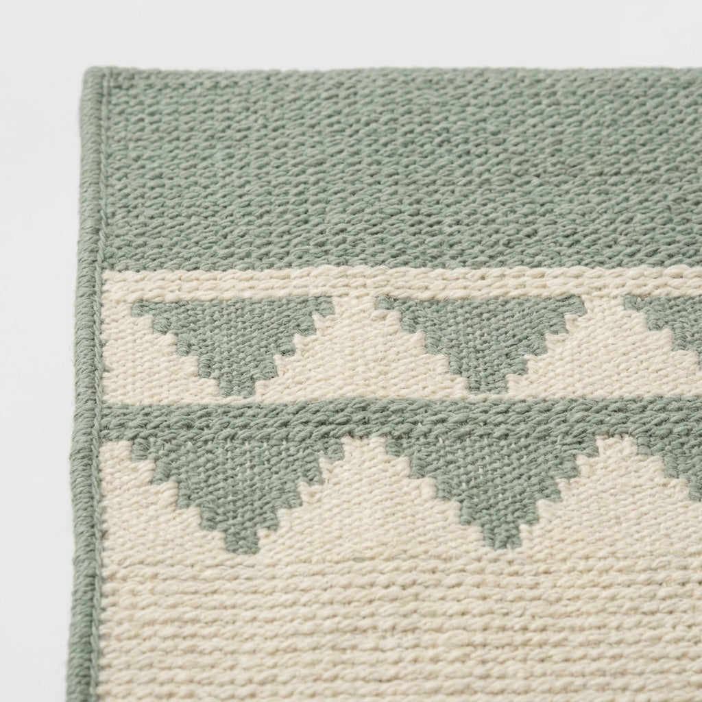 Southwestern Flatweave Wool Rug in sage green and cream, with stepped geometric bands and a textured weave.