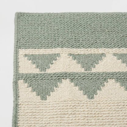 Southwestern Flatweave Wool Rug in sage green and cream, with stepped geometric bands and a textured weave.