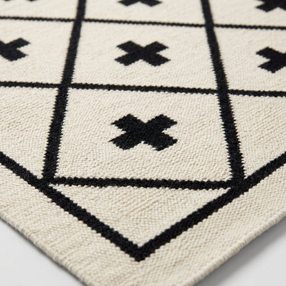 Southwestern Flatweave Wool Rug in ivory with black diamond lattice and bold Swiss cross motifs, woven texture and bordered edge.
