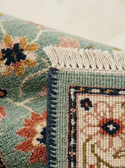 Oushak Hand Knotted Rug in mint green wool with coral, navy and ivory floral motifs, bound edge and cream fringe.