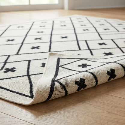 Southwestern Flatweave Wool Rug in ivory with black geometric grid lines and cross motifs, textured weave and rolled edge