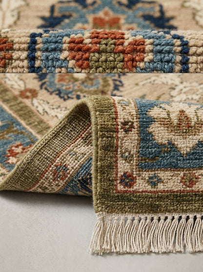 Oushak Hand Knotted Rug in camel beige wool with slate blue and rust floral motifs, bound edge and ivory fringe.