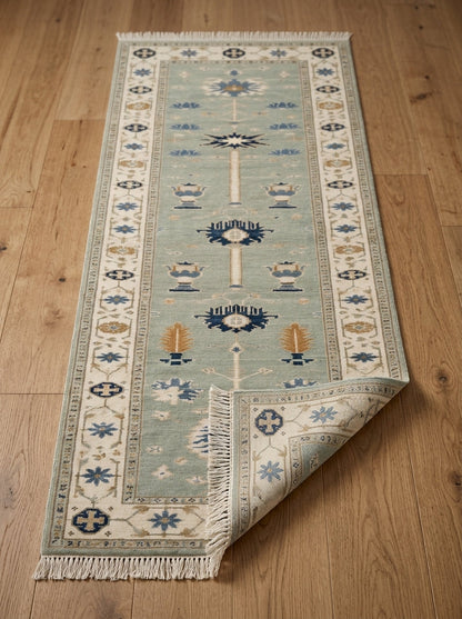 Hand Knotted Oushak Runner Rug in muted seafoam wool, with ivory floral border, navy and amber motifs, and fringed ends.