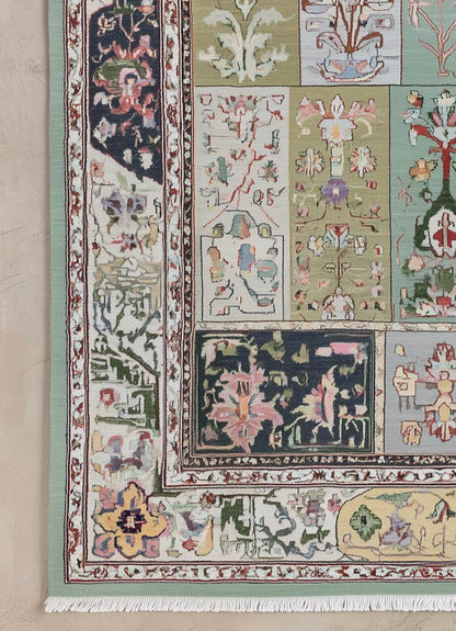 Pastel floral patchwork rug with botanical motifs, mint and navy border, and white fringed edges