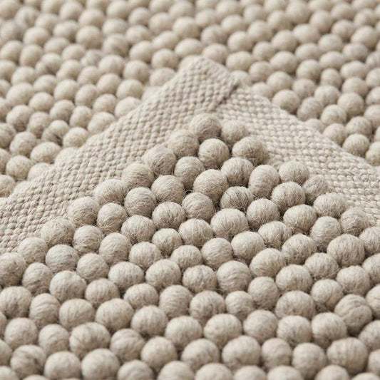 Handwoven pebble weave wool area rug in ivory and beige with textured raised loops for living room decor