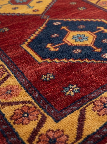 Red Tribal Runner Rug with a deep red wool field, navy and gold geometric medallions, and a golden rosette border