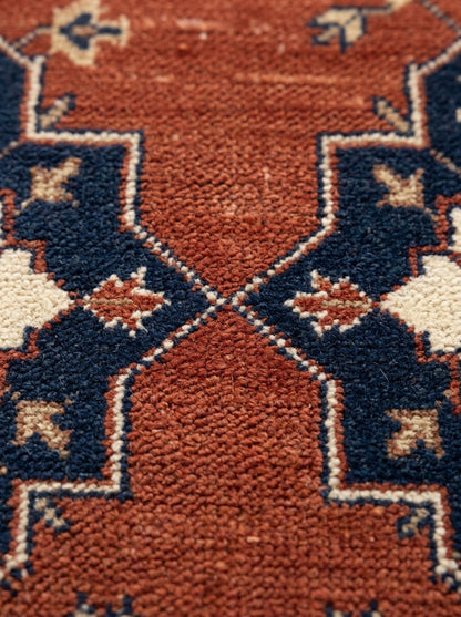 Rust Red Heriz Runner Rug with a textured rust wool field, navy angular medallion details and ivory floral accents