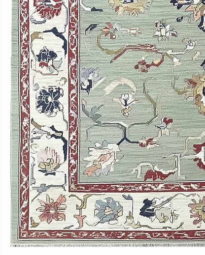 Sage green Oushak rug with floral and vine patterns in hand-tufted wool, featuring muted terracotta, navy, and cream accents.